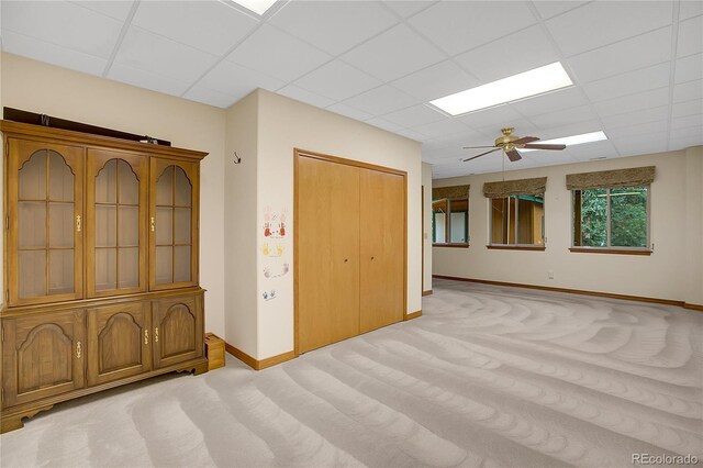 unfurnished room with ceiling fan, light colored carpet, and a drop ceiling