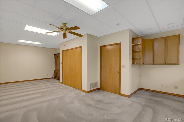 unfurnished bedroom with a paneled ceiling, ceiling fan, and light carpet