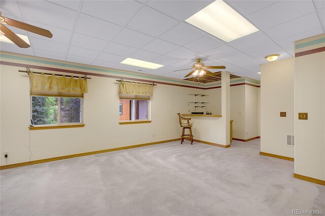 empty room featuring a paneled ceiling, ceiling fan, and light carpet