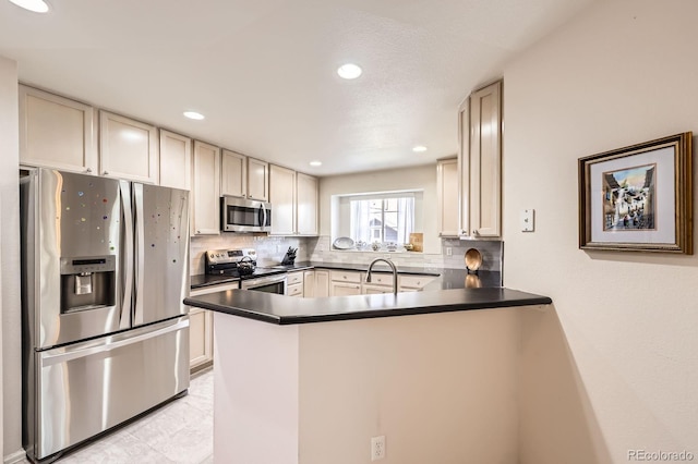 7774 S Biloxi Way, Aurora, CO 80016 - kitchen featuring appliances with stainless steel finishes, a peninsula, tasteful backsplash, dark countertops, and recessed lighting