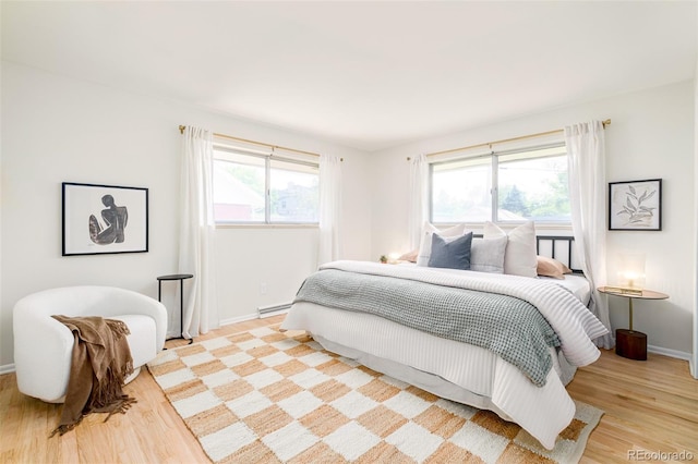 85 S Flower St, Lakewood, CO 80226 - bedroom featuring light wood-type flooring, multiple windows, baseboards, and a baseboard heating unit