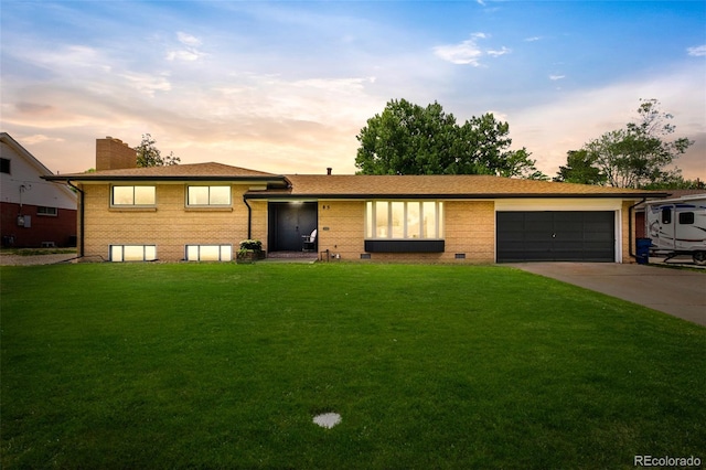 85 S Flower St, Lakewood, CO 80226 - split level home featuring an attached garage, concrete driveway, a front yard, brick siding, and a chimney