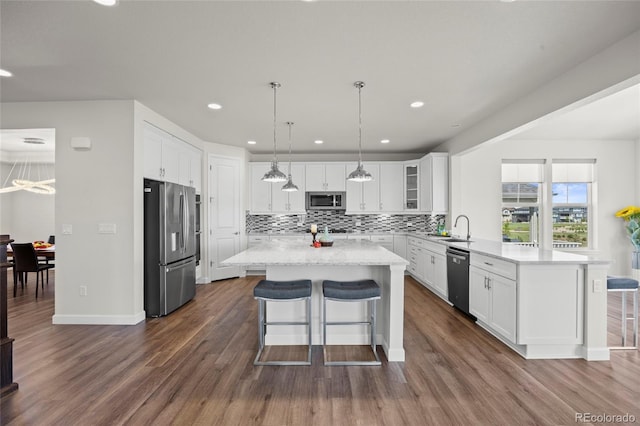 7166 S Vandriver Way, Aurora, CO 80016 - kitchen with appliances with stainless steel finishes, a peninsula, white cabinets, decorative backsplash, and recessed lighting
