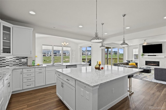 7166 S Vandriver Way, Aurora, CO 80016 - kitchen featuring a kitchen island, recessed lighting, dark wood-style floors, open floor plan, and a glass covered fireplace