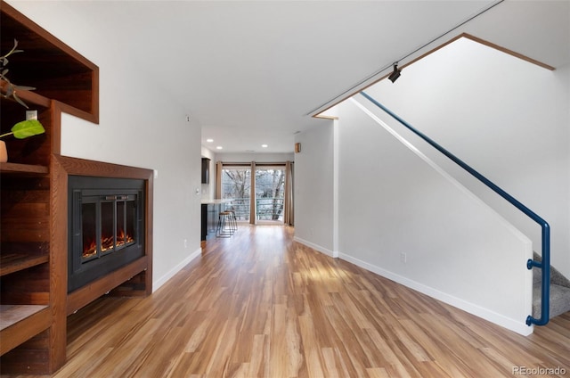 1805 Cheyenne Blvd, Colorado Springs, CO 80906 - unfurnished living room featuring a glass covered fireplace, recessed lighting, baseboards, wood finished floors, and stairway