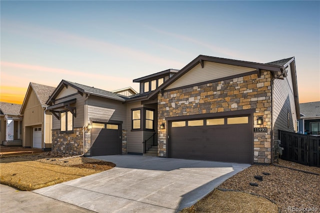 view of front of house with fence, concrete driveway, a garage, and stone siding