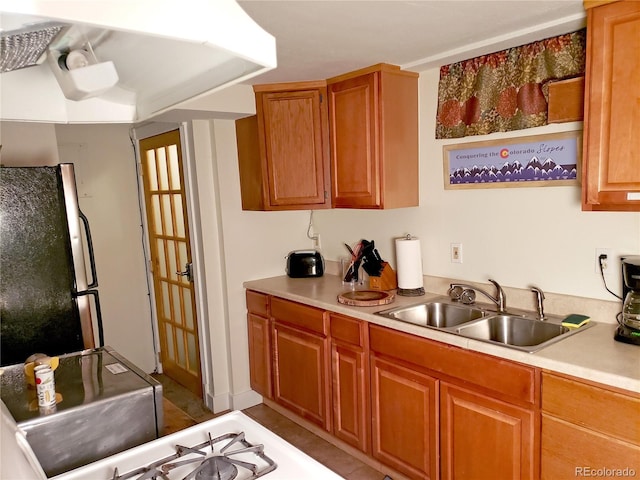 kitchen featuring stainless steel refrigerator, sink, and light tile patterned floors