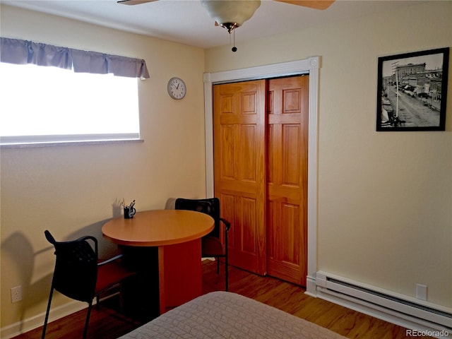 bedroom featuring ceiling fan, hardwood / wood-style flooring, a closet, and a baseboard heating unit