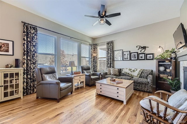 living room featuring ceiling fan, a fireplace, and light hardwood / wood-style floors