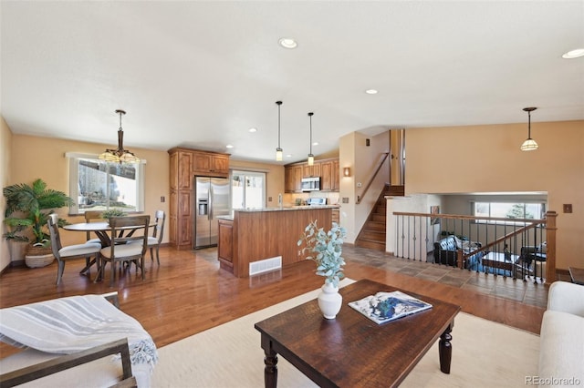 living room featuring vaulted ceiling, stairway, light wood-style floors, and a wealth of natural light