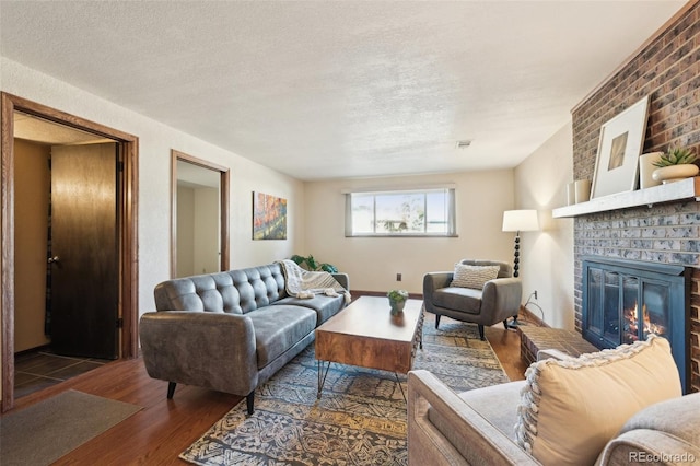 living area with wood finished floors, a fireplace, visible vents, and a textured ceiling