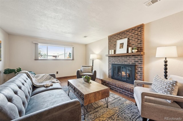 living room with visible vents, a textured ceiling, wood finished floors, and a fireplace