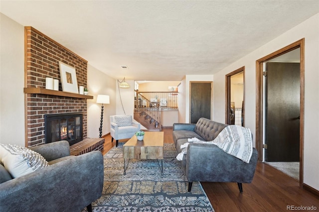 living room with a fireplace, stairs, wood finished floors, and a textured ceiling