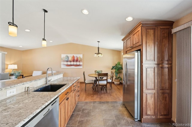 kitchen featuring light stone countertops, lofted ceiling, recessed lighting, appliances with stainless steel finishes, and a sink