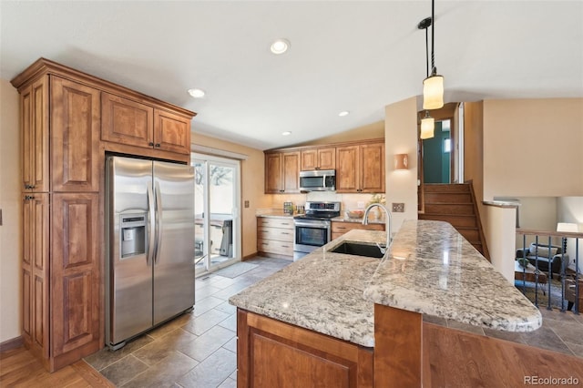 kitchen with a sink, decorative light fixtures, stainless steel appliances, brown cabinetry, and light stone countertops