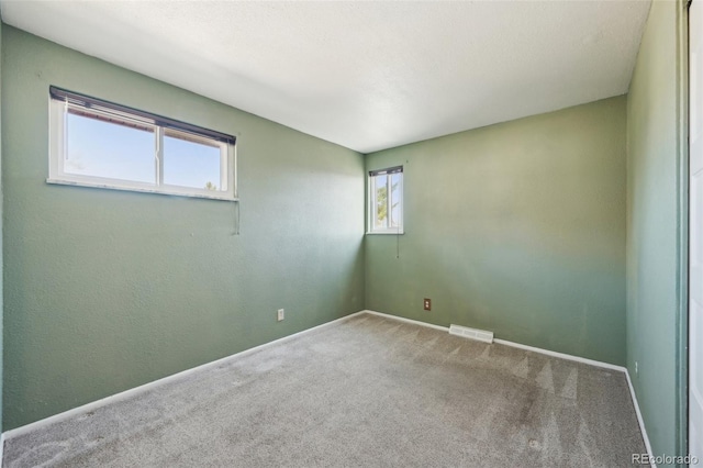 carpeted spare room with visible vents and baseboards