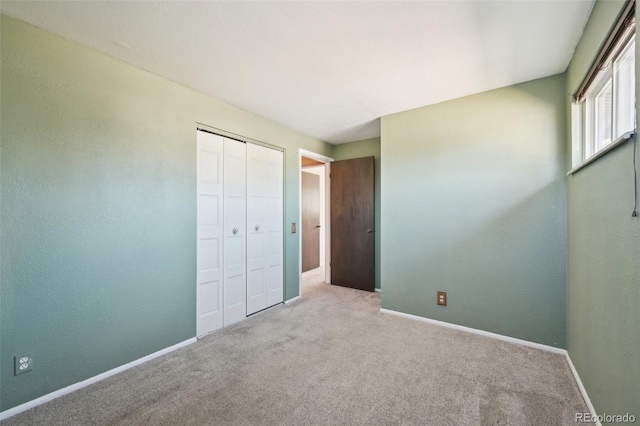 unfurnished bedroom featuring a closet, baseboards, and carpet floors