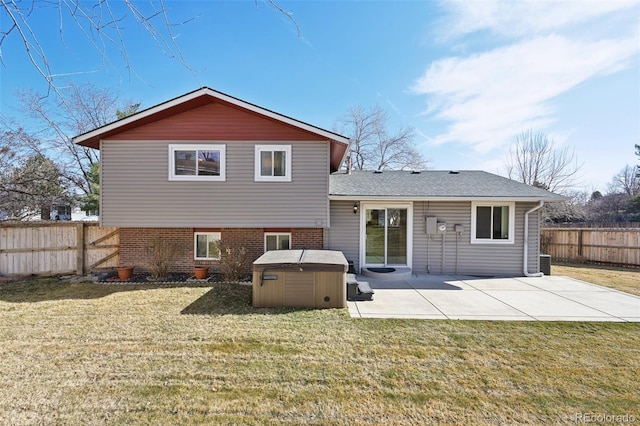 rear view of house featuring a patio, a yard, a fenced backyard, a hot tub, and brick siding