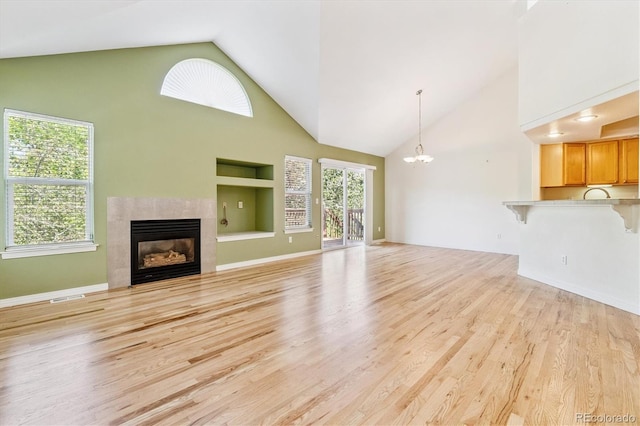 2330 S Salem Cir, Aurora, CO 80014 - unfurnished living room featuring high vaulted ceiling, a chandelier, a tile fireplace, and light wood finished floors