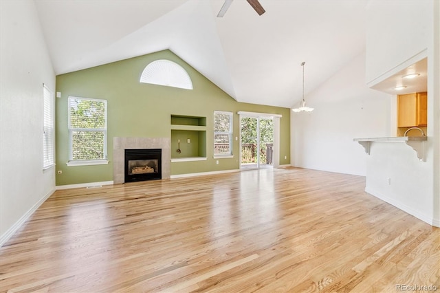 2330 S Salem Cir, Aurora, CO 80014 - unfurnished living room featuring a tile fireplace, healthy amount of natural light, light wood-style flooring, high vaulted ceiling, and a ceiling fan