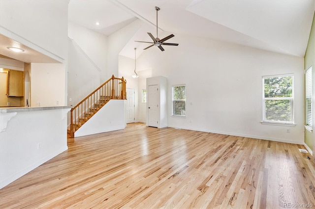 2330 S Salem Cir, Aurora, CO 80014 - unfurnished living room with high vaulted ceiling, healthy amount of natural light, stairs, light wood finished floors, and ceiling fan