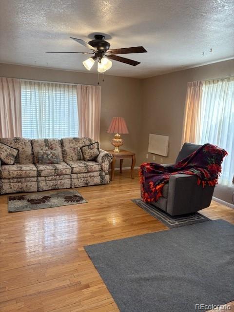 living area featuring a textured ceiling, wood finished floors, and a ceiling fan