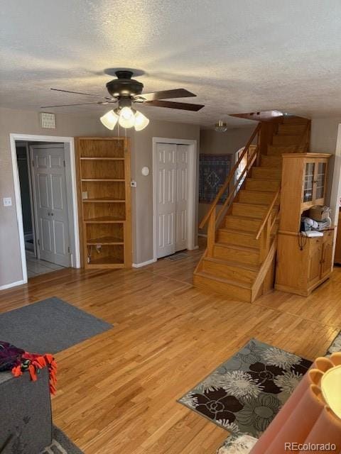 living area with a textured ceiling, stairway, and wood finished floors