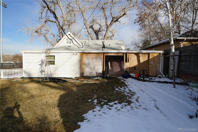 snow covered property featuring a lawn and fence