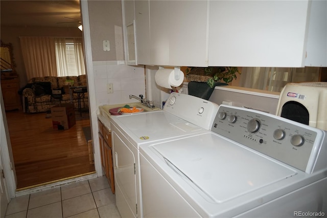 laundry room featuring cabinet space, light tile patterned floors, ceiling fan, washing machine and clothes dryer, and a sink