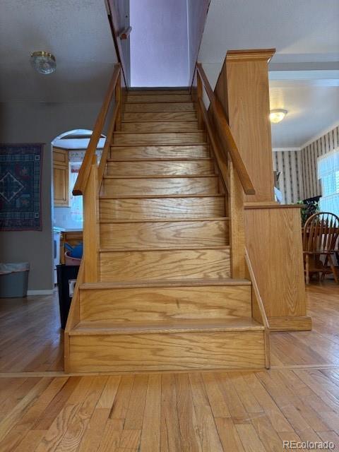 stairs with arched walkways and wood finished floors