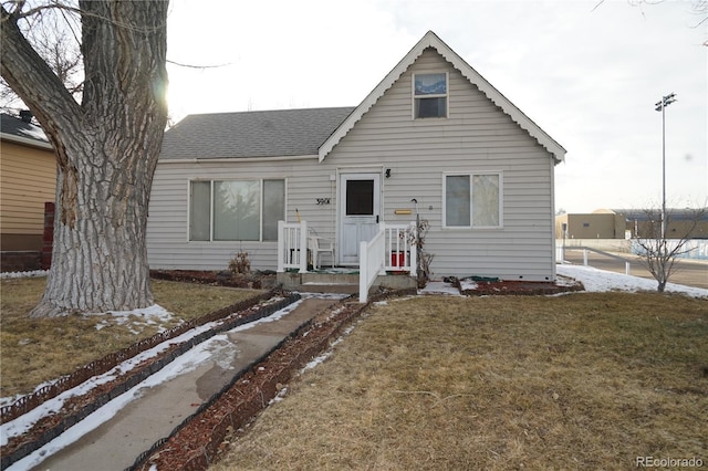 bungalow featuring a front lawn and a shingled roof