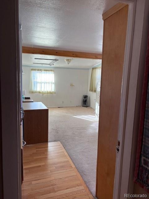 interior space featuring beamed ceiling, a textured ceiling, and light colored carpet