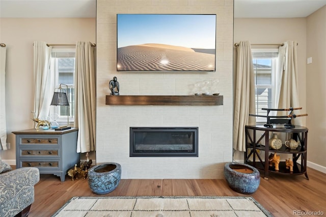 6980 S Yantley Ct, Aurora, CO 80016 - living area featuring wood finished floors, healthy amount of natural light, a tile fireplace, and baseboards