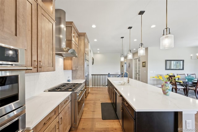 6980 S Yantley Ct, Aurora, CO 80016 - kitchen with appliances with stainless steel finishes, a sink, wall chimney range hood, light wood-style floors, and recessed lighting