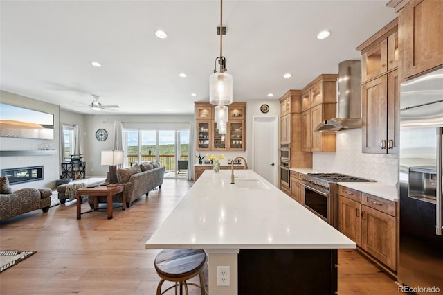 6980 S Yantley Ct, Aurora, CO 80016 - kitchen with high end appliances, wall chimney exhaust hood, a sink, open floor plan, and recessed lighting