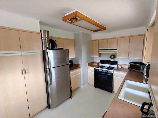 7409 Pierce St, Arvada, CO 80003 - kitchen with freestanding refrigerator, gas stove, light brown cabinets, under cabinet range hood, and cream cabinets