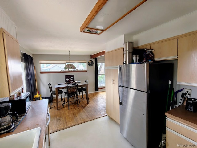 7409 Pierce St, Arvada, CO 80003 - kitchen featuring freestanding refrigerator, healthy amount of natural light, light brown cabinetry, and pendant lighting