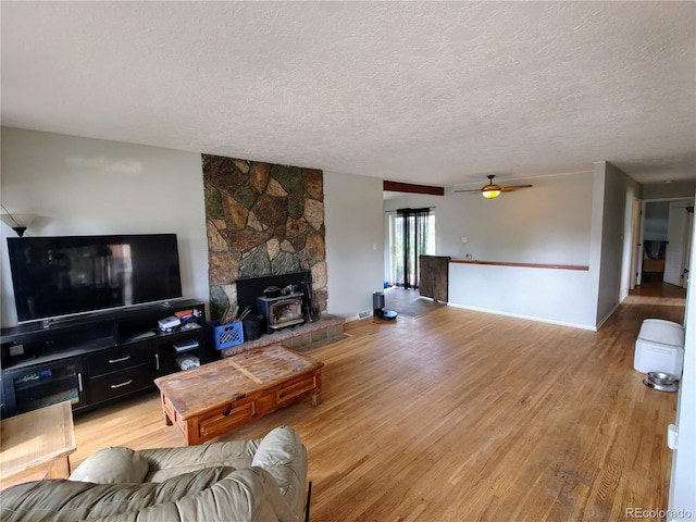 7409 Pierce St, Arvada, CO 80003 - living area featuring a textured ceiling, a wood stove, ceiling fan, and light wood-style floors