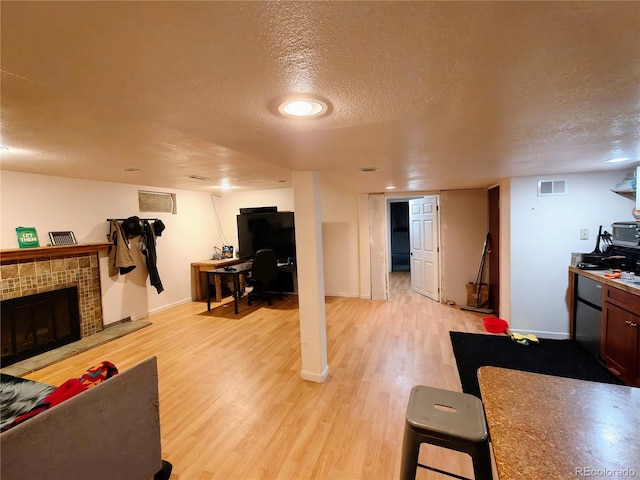 7409 Pierce St, Arvada, CO 80003 - living room with a textured ceiling, light wood finished floors, and a tiled fireplace