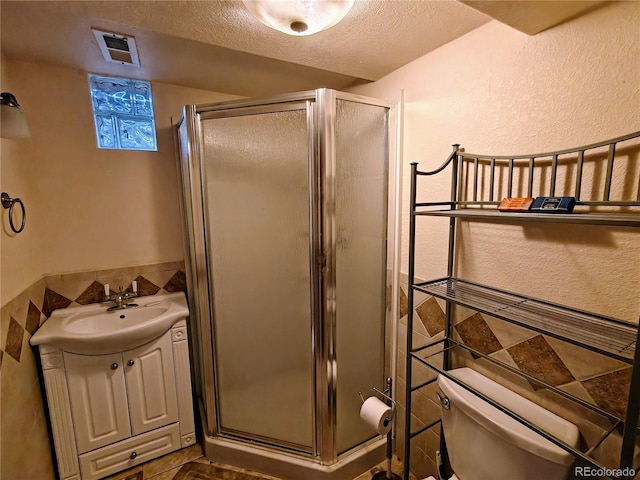 7409 Pierce St, Arvada, CO 80003 - full bathroom featuring a stall shower, a textured ceiling, tile walls, and vanity