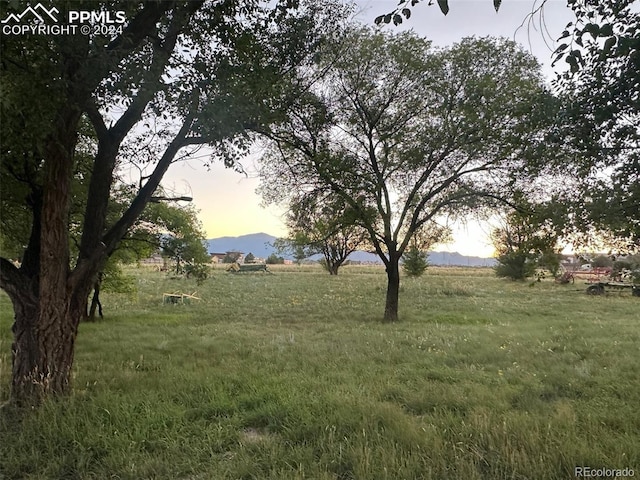 yard at dusk featuring a mountain view and a rural view