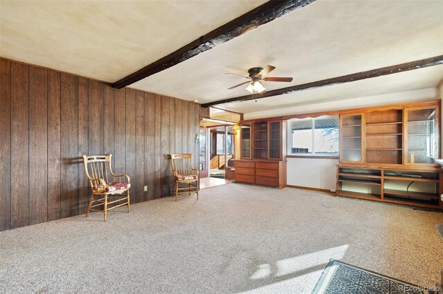 unfurnished room with wood walls, ceiling fan, and beam ceiling