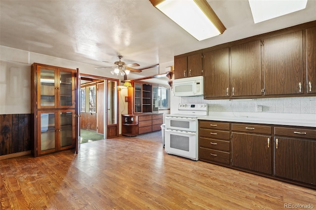 kitchen featuring light wood-type flooring, white appliances, tasteful backsplash, and a healthy amount of sunlight