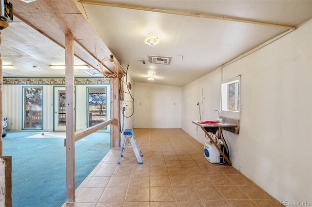 basement featuring sink, a healthy amount of sunlight, and light tile patterned flooring