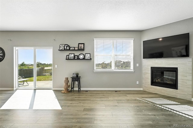 1670 Vantage Pkwy, Berthoud, CO 80513 - unfurnished living room with wood finished floors, plenty of natural light, a tiled fireplace, and a textured ceiling