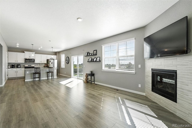 1670 Vantage Pkwy, Berthoud, CO 80513 - unfurnished living room featuring a tiled fireplace, wood finished floors, and a textured ceiling