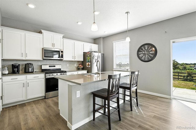 1670 Vantage Pkwy, Berthoud, CO 80513 - kitchen featuring stainless steel appliances, backsplash, wood finished floors, an island with sink, and a breakfast bar area
