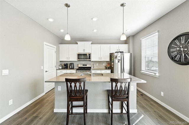 1670 Vantage Pkwy, Berthoud, CO 80513 - kitchen featuring appliances with stainless steel finishes, a center island with sink, dark wood-type flooring, white cabinets, and a breakfast bar area