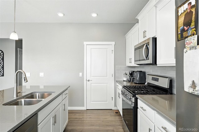 1670 Vantage Pkwy, Berthoud, CO 80513 - kitchen featuring appliances with stainless steel finishes, dark wood-type flooring, tasteful backsplash, white cabinets, and hanging light fixtures