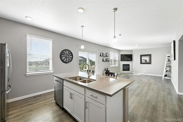 1670 Vantage Pkwy, Berthoud, CO 80513 - kitchen with appliances with stainless steel finishes, wood finished floors, decorative light fixtures, white cabinetry, and a center island with sink
